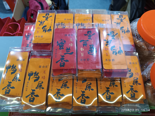 Ein Tisch mit verschiedenen verpackten Lebensmitteln und Gegenständen bei einer Feier zum chinesischen Neujahr, im Hintergrund steht eine Person.