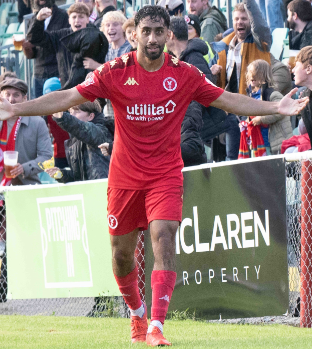 Ein Fußballspieler in roter Uniform rennt auf einem Feld mit ausgestreckten Armen, umgeben von Zuschauern im Hintergrund, mit einem Banner "Middlesbrough FC v Swansea City - Sky Bet Championship" im Vordergrund.