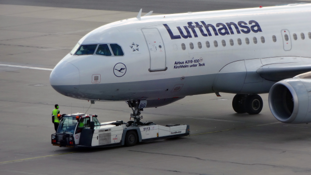 Ein Lufthansa Airbus A319-100 steht auf dem Rollfeld am Frankfurter Flughafen, mit einem Fahrzeug und einer Person in der Nähe, bereit zum Abflug.