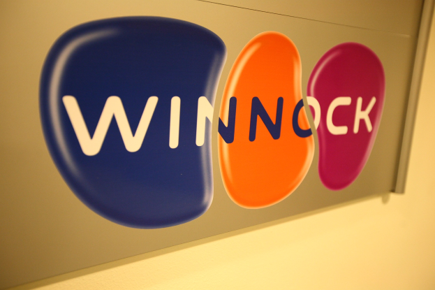 Hell leuchtendes "Winnock"-Schild an einer Wand angebracht, das auf einen Aktienmarkt hinweist.
