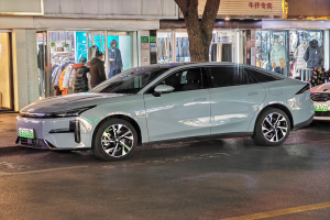 Ein Mitsubishi Lancer EV-Elektroauto nachts auf einer Straße geparkt, umgeben von Gebäuden, Geschäften, Schaufensterpuppen mit Kleidern, Schildern, Lichtern und anderen Gegenständen.