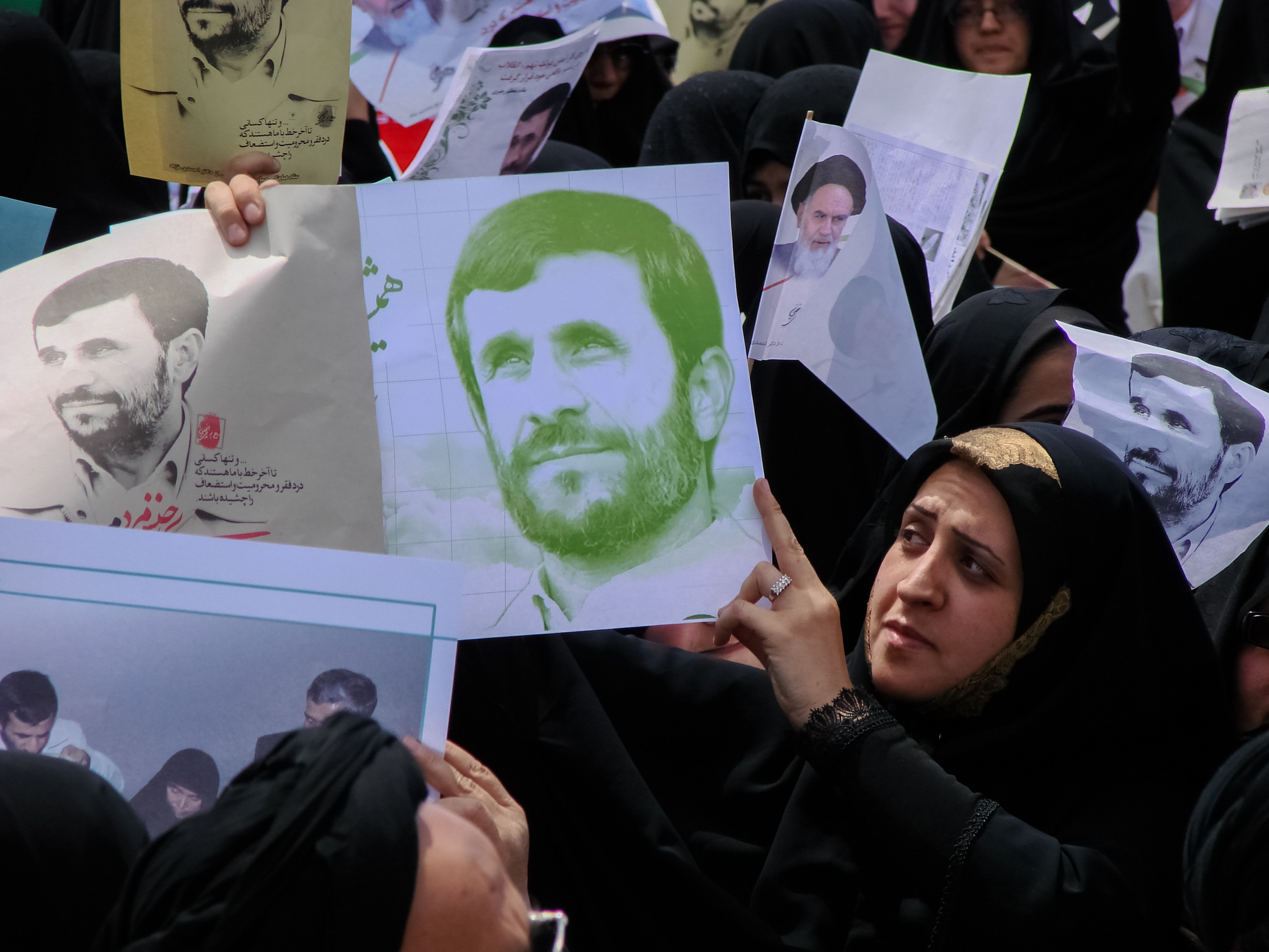 Eine Gruppe iranischer Frauen in schwarzer Kleidung, einige mit Brille, halten Fotos von Präsident Mahmud Ahmadinedschad während einer Demonstration in Teheran hoch.