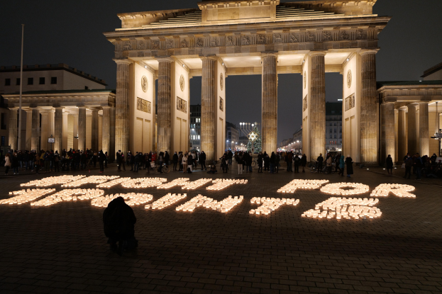Menschen vor dem beleuchteten Brandenburger Tor in Berlin, Deutschland, mit der Aufschrift "Kampf für die Freiheit" auf dem Boden.
