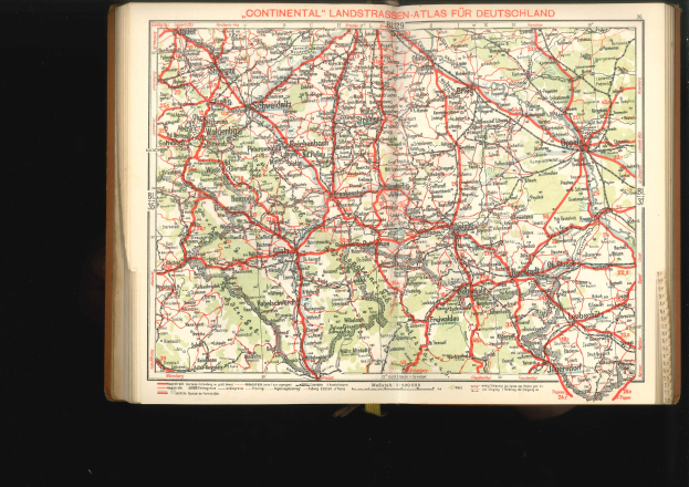Offenes Buch mit detaillierter Karte von Deutschlands Straßen und Autobahnen auf schwarzem Hintergrund.