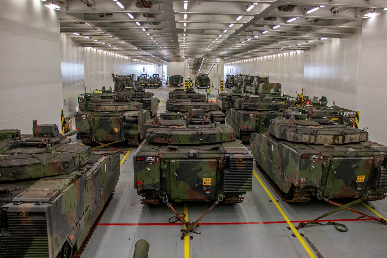 Eine gro├če Militargelandehalle mit Reihen von Militartanks, Wanden an beiden Seiten und Deckenbeleuchtung.