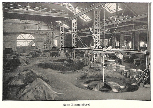 Schwarzes und weißes Foto einer Fabrik mit Arbeitern, die Maschinen bedienen, umgeben von Metallstangen und -pfählen, beschriftet mit "Neue Eisengießerei, die erste Fabrik Deutschlands."