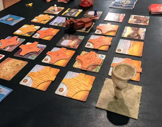 Ein unordentlicher Tisch mit Star Wars: The Old Republic-Spielkarten, Spielzeugen und Gegenständen in einem Raum mit einer sichtbaren Wand im Hintergrund.