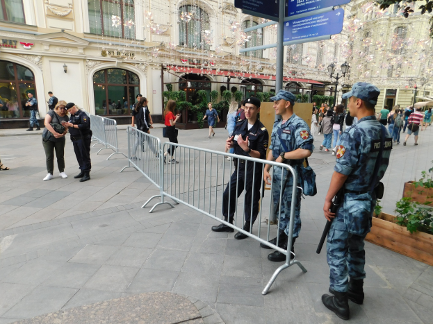 Polizeibeamte in Uniform stehen hinter Absperrungen und blicken einer Menge entgegen, von denen einige Mützen tragen und Waffen tragen, während sie eine Anti-Terror-Operation in Wien, Österreich, durchführen.