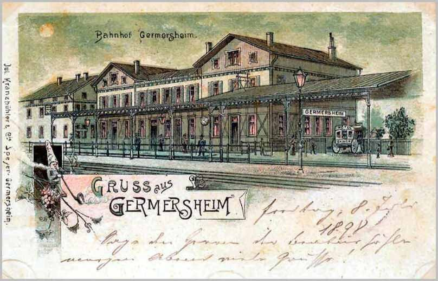 Schwarze und weiße Postkarte des Bahnhofs Germersheim in Deutschland, die ein Gebäude, Menschen, Fahrzeuge, Bäume, einen Zaun, einen Straßenpfahl und einen bewölkten Himmel zeigt.