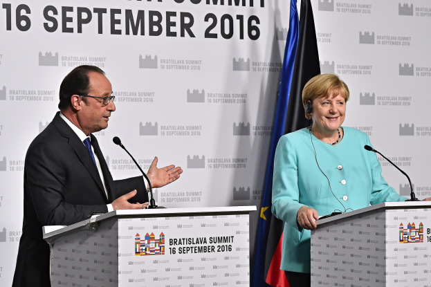 Bundeskanzlerin Angela Merkel und Frankreichs Präsident François Hollande stehen vor zwei Podien mit Mikrofonen, beide lachend, mit einem "Bratislava-Gipfel 2016"-Schild dahinter.