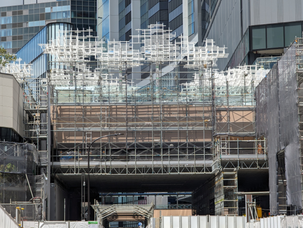 Gro├čes Geb├Ąude mit Gerüst in einer urbanen Umgebung.