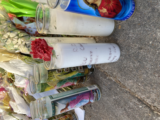 Eine improvisierte Straßenrandgedenkstätte mit Glasflaschen mit Fotos und Texten, einem Blumenstrauß und angezündeten Kerzen.