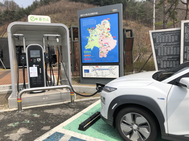 Elektrisches Auto an einer Ladestation in Seoul, Südkorea, umgeben von Bäumen mit Himmel im Hintergrund.